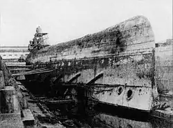 A large ship upside-down and braced in a drydock