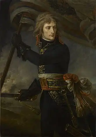 A three-quarter-length depiction of Bonaparte, with black tunic and leather gloves, holding a standard and sword, turning backwards to look at his troops