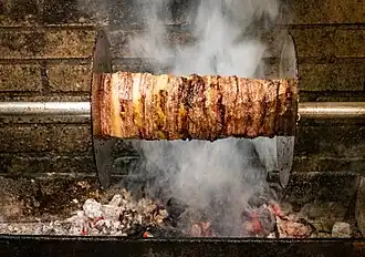 Horizontally roasted shawarma being cooked over coals