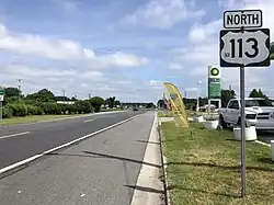 A four-lane asphalt divided highway in an area of businesses