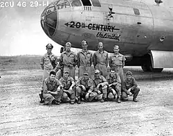 A black and white photograph of two rows of uniformed men standing in front of an aircraft. 6 crouching men are in the front row and 5 standing men are in the rear row