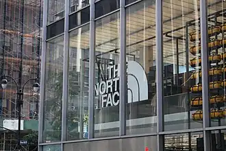 The North Face store in the building as seen from outside. Behind the windows is the North Face logo and some merchandise.