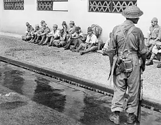 Indian soldier guards Japanese prisoners in Singapore