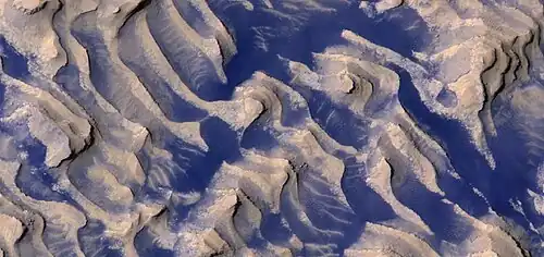Close, color view of layers and dark dust on floor, as seen by HiRISE. Boulders are visible in the image.