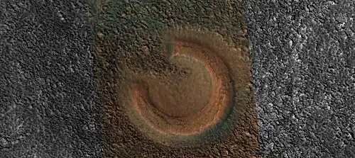 Close view of mud volcano, as seen by HiRISE. Picture is about 1&nbsp;km across. This mud volcano has a different color than the surroundings because it consists of material brought up from depth. These structures may be useful to explore for remains of past life since they contain samples that would have been protected from the strong radiation at the surface.