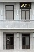 A 2008 closeup of the sign hanging outside the 2nd floor of the building. A North Korean soldier is seen guarding the first floor entrance.