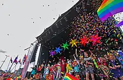 Many people on a stage with rainbow colors everywhere