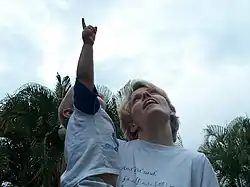 A boy pointing at sky with mother, who is holding him