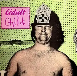 A saturated image of Brian Wilson in a fire hat on with the words "Adult/Child" written in a pink box next to him