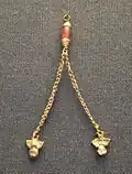 Gold ornament with two chains ending in owl figurines