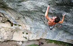 A climber using the knee-bar technique on an indoor climbing wall