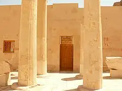 A large stone wall with a closed entrance and two rows of two columns preceding it
