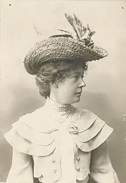 Black and white half-length photo of a woman wearing a straw hat, head in profile looking right