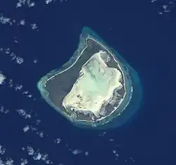 Astove Atoll, slightly oblique view from space. Note the wide land area (dark) surrounding the whitish lagoon