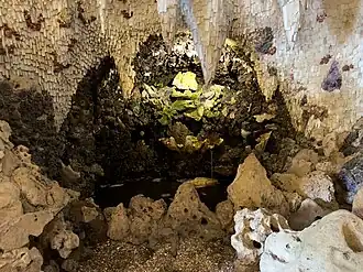 Water falling from the sloped side of a cavern into a pool below