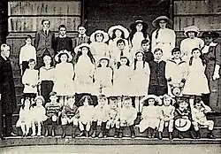 A black and white photo of about 30 children of varying ages lined up in rows.