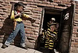 A girl dressed as Lucky Luke points a revolver at other children dressed as The Daltons.