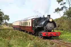 Steam locomotive No. 4 hauls a small tourist train down a straight portion of the railway