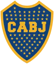 A Blue shield with a golden border. Inside the shield, 67 stars inside the shield with the golden letters "CABJ" (meaning "Club Atlético Boca Juniors") printed around the center, separating the stars