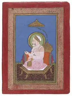 A color portrait of an old bearded man, seated on a throne and wearing a turban