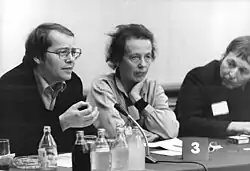 Volker Braun (left), alongside Ruth Berghaus (center) and Wieland Förster in Berlin 1981. The image was taken by the Signum photographer Peter Heinz Junge and is deposited in the German Federal Archives
