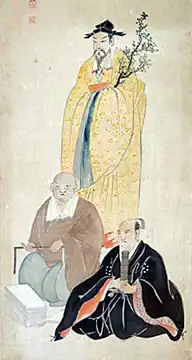 One man standing behind two seated men; they all are in particularly formal garb