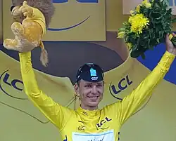 A man wearing a yellow jersey with his arms aloft.