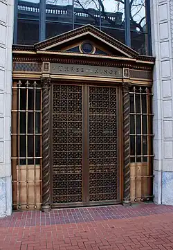 An entrance showing ornate bronze work on and around the gates covering the doors
