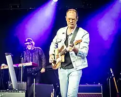 Musician Charles Spearin holding a microphone onstage at a concert in 2008