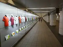 Image of a long display case made of glass containing suits mounted against the wall.
