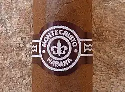Close photograph of a label on a cigar featuring a fleur-de-lis surrounded by the text "MONTECRISTO · HABANA".