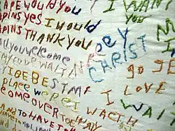 Textile art embroidered by a person diagnosed with schizophrenia, showing non-linear text with multiple colors of thread