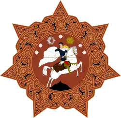 A round orange badge with six points and a horse-mounted man in the centre