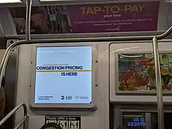 A subway electronic ad board reading "congestion pricing is here"