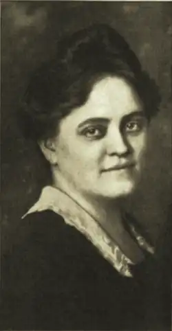B&W portrait photo of a woman with fair skin and dark hair in an updo, wearing a dark blouse with white collar