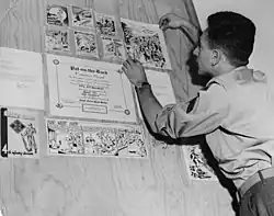 Circa 1953, Corporal Ed Seeman putting up a display of his artwork and the award, "A Pat on the Back."