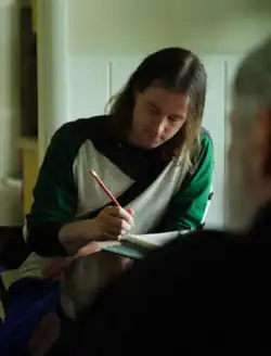 Derek Piotr taking fieldnotes while recording a traditional singer.