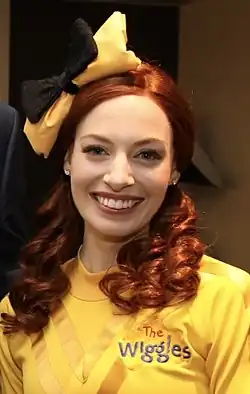 Watkins posing and smiling in her yellow costume for The Wiggles