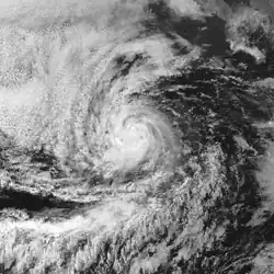 A photograph of a tropical storm over the Eastern Pacific Ocean; it has a tightly wound circulation with spiral banding and high clouds visible to the south and northwest