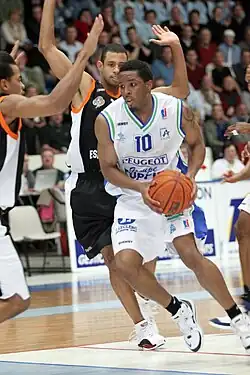 Errick Craven during a game of basketball in 2006. He hold the ball and is surrounded by 2 opponents.