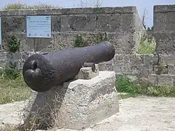 19th-century cannon, set in the wall of Acre near a sign commemorating Farhi. The Hebrew inscription on the sign reads: "Farhi vs. Napoleon. Jezzar's right hand in resisting Napoleon's harsh siege was the Jewish Haim Farhi, senior adviser and minister of finance"