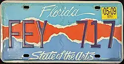 This plate says "Florida" on the top, "State of the Arts" at the bottom, and incorporates a colored design that is teal on the top, blue on the bottom, and red in the middle.