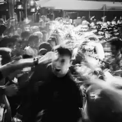A grayscale image of Fred Again yelling in a crowd at a rave