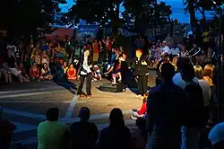 Two men gesture outside as they perform for a crowd