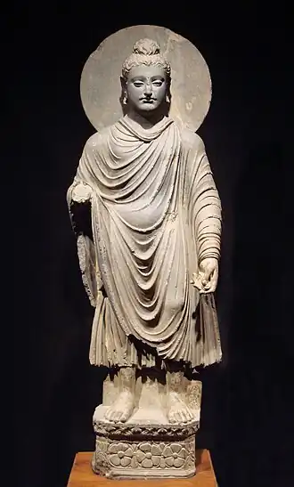 The Buddha wearing kāṣāya robes, originating from ancient India. These robes were worn by fully ordained Buddhist monks and nuns.
