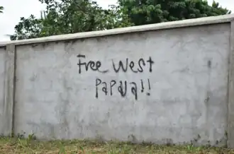 This is a photo of unlicensed graffiti in Vanuatu advocating for the liberation of West Papua. There is graffiti on a light-grey wall which says 'Free West Papua!!'. This photo reflects the international support for the self-determination of West Papuans. This photo was taken in Vanuatu on 5 February 2018.