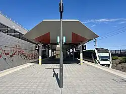 Tiled station platform with large architectural shelter and trains docked at both sides