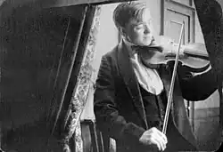 A man seated playing a violin