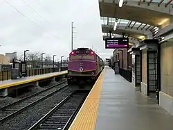 A passenger train leaving a station with two tracks and two platforms