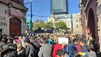 A crowd of protesters in front of soldiers and military vehicles